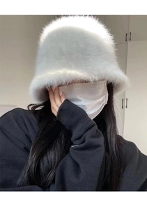 Close-up of a white fluffy faux fur bucket hat showing its soft, plush winter texture