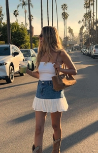 Outdoor street view of a blue denim mini skirt with white lace patchwork and western boots