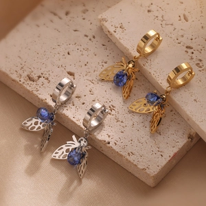 Gold and silver bee drop earrings with blue zircon stones on a natural stone base