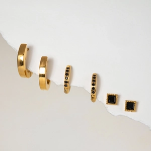 Detailed view of 3-piece gold stainless steel earring set with black stones and studs