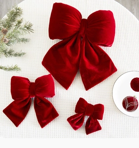 Three sizes of red velvet bows for festive decor with pine cones on grid background