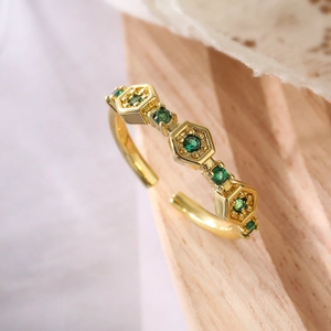 Macro shot of gold-plated geometric honeycomb ring with sparkling green zircon stones