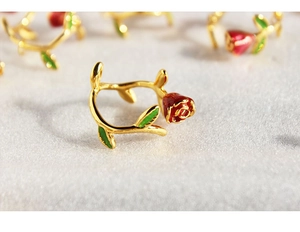 Macro shot of French enamel red rose ring with golden vine band and green leaves