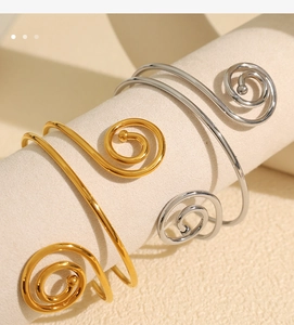 Detailed view of spiral open bangles in gold and silver finish on jewelry display