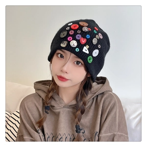 Detail of black knitted beanie featuring colorful decorative buttons and heart shapes