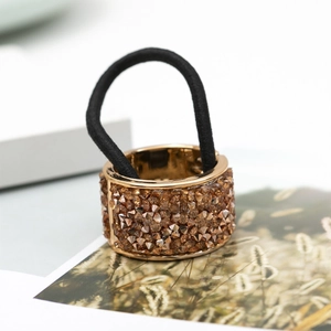 Close-up of golden metal hair cuff with champagne crystals and black elastic band