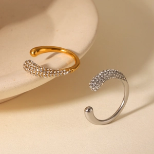 Macro shot of gold and silver open rings with pavé cubic zirconia on minimalist ceramic
