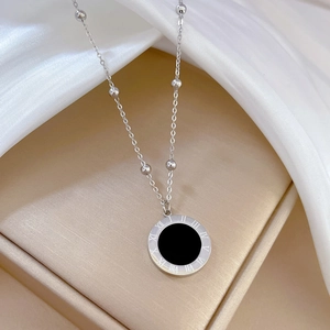 Macro detail of silver titanium steel necklace with Roman numeral shell pendant on satin