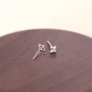 Minimalist square silver stud earrings with clear zircon on a rustic wooden plate