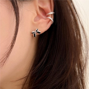 Close-up of bow earrings and sparkling ear cuffs set on a model ear