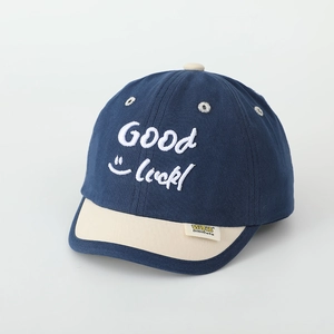 Detail of kids baseball cap with navy crown, cream brim and Good Luck embroidery