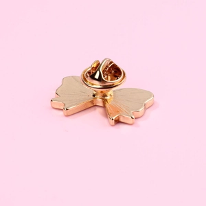 Detail of a golden metal bow brooch with a secure butterfly clutch pin back