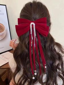 Dettaglio del fiocco in velluto rosso con nappe di strass e perle sui capelli lunghi