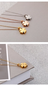 Detailed close-up of clover pendant necklace with zircon inlay in three metallic colors