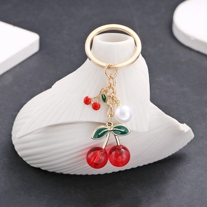 Detail of red cherry pendant keychain with white pearl on elegant shell vase display