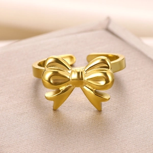 Macro shot of a polished golden bow open ring on a textured metallic surface