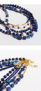Close-up of blue lapis beads, baroque pearls and gold clasp on a layered necklace