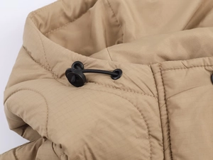 Détail de veste matelassée kaki avec capuche à cordon réglable et texture de tissu ripstop