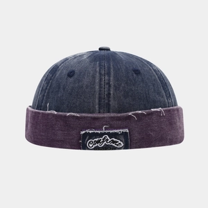 Detailansicht der Denim-Docker-Mütze mit lila Krempe und besticktem Logo-Aufnäher