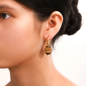 Elegant gold earrings with oval tiger eye stone pendants shown on model profile