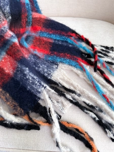 Close-up of soft plaid scarf showing fuzzy wool texture and fringe tassel detail