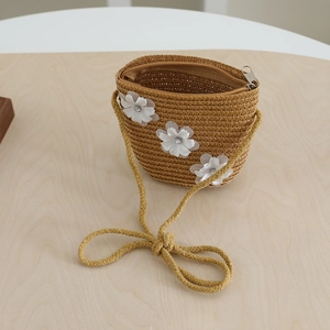 Detail of a straw mini crossbody bag with white fabric flowers and metal zipper for kids