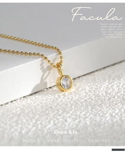 Close-up of a gold solitaire zircon pendant necklace on a bead chain with metal texture
