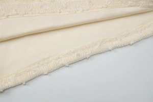 Detail shot of off-white fabric showing delicate lace trim and refined stitching texture