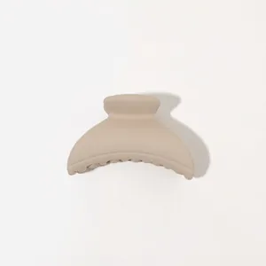 Detail of matte beige hair claw clip with rounded design and smooth frosted texture