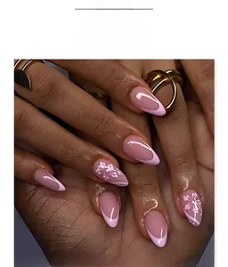 Detailed shot of pink French almond press on nails with hand-painted white flower designs
