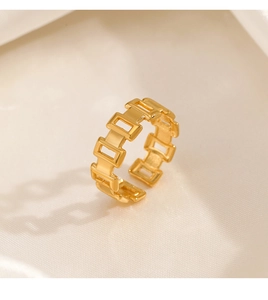 Macro detail of gold plated geometric hollow link chain ring on silk fabric