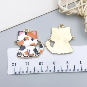 Detail of calico cat alloy pendant with dimensions shown on a ruler for DIY jewelry