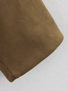 Détail macro du tissu suédine marron caramel avec couture fine et texture de surface