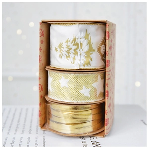 Three rolls of Christmas glitter ribbons in gold and cream for festive gift wrapping decor