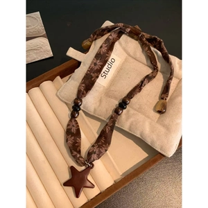 Detail of star pendant necklace with floral fabric cord and rustic wooden beads