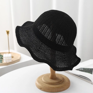 Detail of black hollow knit sun hat featuring elegant wavy wide brim and crochet texture