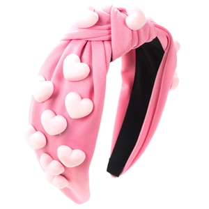 Detail of pink knotted fabric headband featuring soft 3D plush hearts decoration