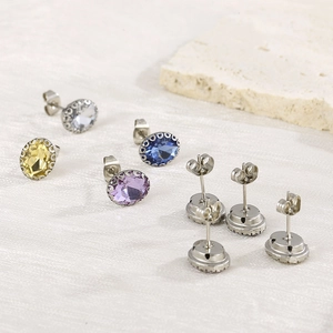 Macro view of oval-cut rhinestone earrings in multiple colors on white fabric