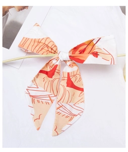 Close-up of geometric pattern silk ribbon scarf tied as a bow on a wooden branch