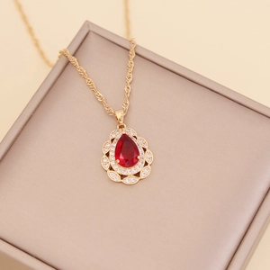 Detail of a red teardrop crystal pendant with small diamonds on a gold chain