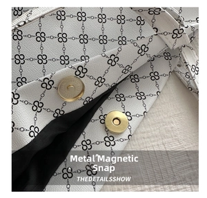 Detail of magnetic snap closures and logo pattern on stylish white faux leather tote