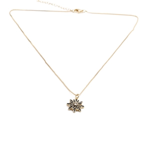 Detail of a minimalist gold daisy necklace with a black and gold flower pendant