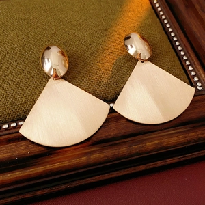 Macro detail of rose gold fan-shaped drop earrings with brushed metal texture