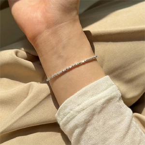 Detail of S925 sterling silver crushed silver bracelet worn on wrist with white knit sleeve
