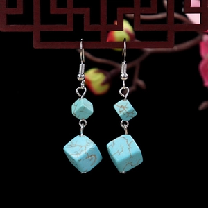 Macro detail of turquoise square drop earrings with silver metal on ethnic wood frame