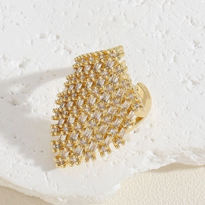 Close-up of golden geometric ring with baguette-cut zircons on a white stone base