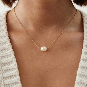 Close-up of elegant gold layered necklace featuring a classic white pearl pendant for women
