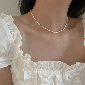Close-up of minimalist freshwater pearl necklace on neck showing tiny cream pearls