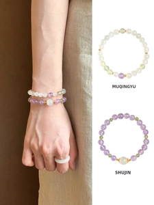 Detail of amethyst and prehnite beaded bracelets with golden spacers and jade ring