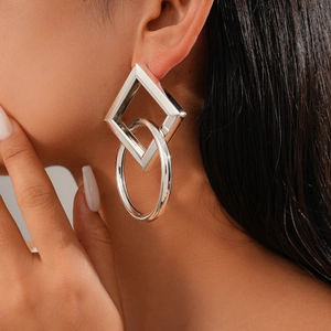 Detail view of geometric silver earrings with linked square and circle studs on model